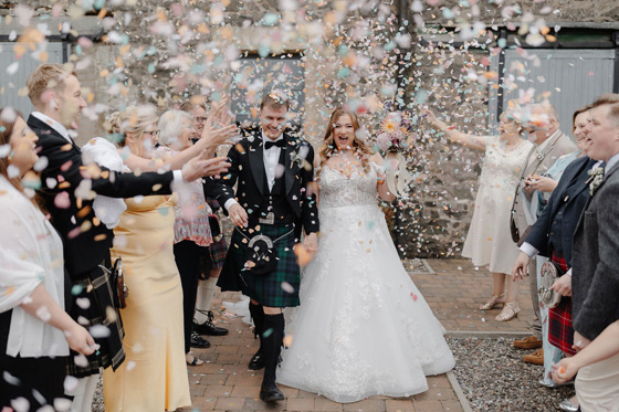 Bride and groom walk through confetti